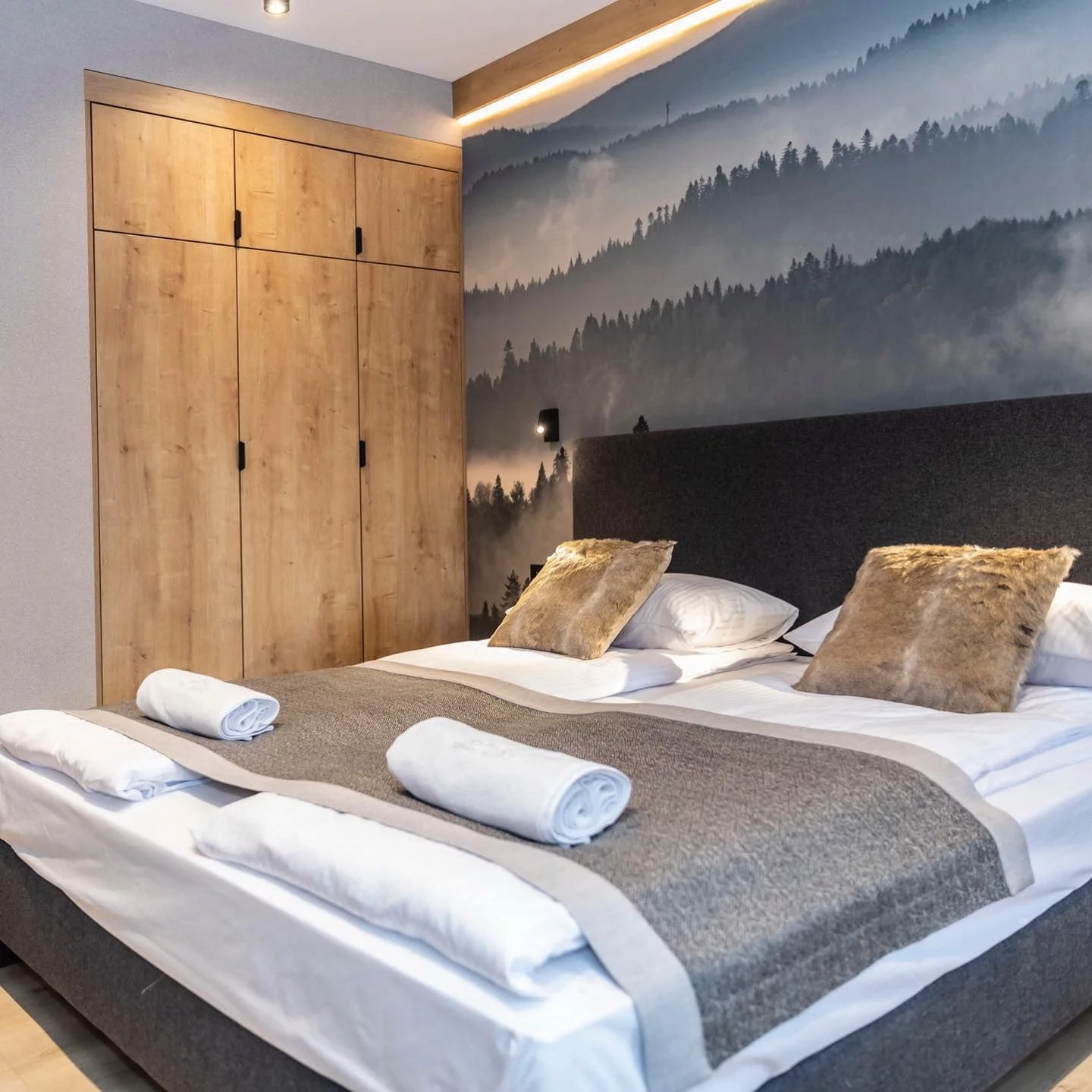 Doppelbett mit dunkelgrauem Kopfteil und Bettbox vor Fototapete